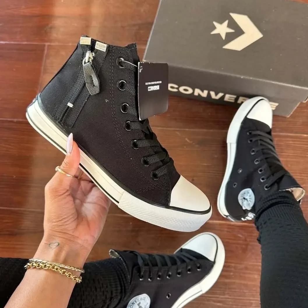 O Chuck 70 cano alto com zíper na mão, ao lado da caixa da Converse